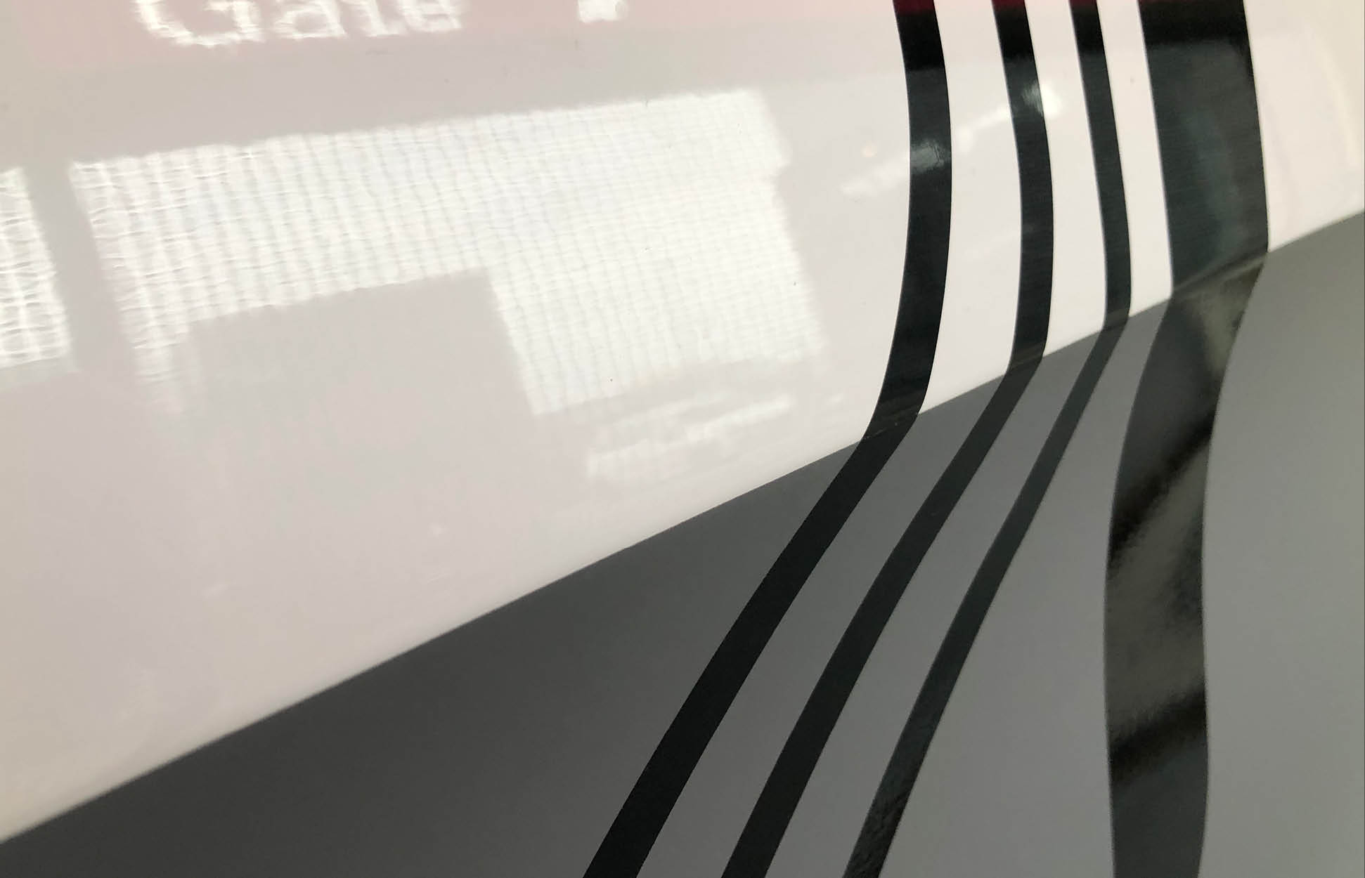Fahrzeugfolierung Detail – präzise Linien und hochwertiges Design Detail einer Fahrzeugfolierung mit schwarzen Linien auf heller Oberfläche