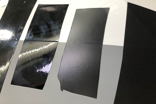 Fahrzeugfolierung – Material- und Oberflächenvergleich Vergleich verschiedener schwarzer Folienmuster auf grauer Fahrzeugoberfläche während der Designvorbereitung