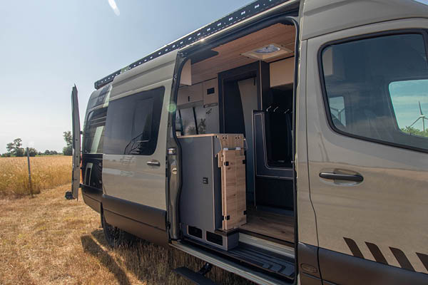 Mercedes Sprinter Camper – Innenraum mit geöffneter Tür Mercedes Sprinter Camper mit geöffneter Schiebetür und Blick auf den Innenraum mit Holzausbau