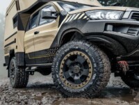 Expeditionsfahrzeug Offroad – Detailaufnahme Folierung & Schlamm-Action | VÄN Nahaufnahme eines Expeditionsfahrzeugs mit sandfarbener und schwarzer Folierung, verschlammten Offroad-Reifen und robusten Designelementen im Gelände