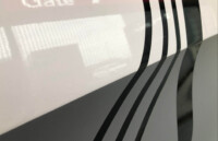 Nahaufnahme Wohnmobil-Folierung – hochwertiges Linien-Design | VÄN Nahaufnahme einer hochwertigen Fahrzeugfolierung mit schwarzen und grauen Linien auf weißer Oberfläche – präzise Kanten und glatte Struktur