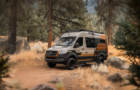 vaen_graphics_projekte019 Mercedes Sprinter Camper mit linienförmiger orange/schwarzer Folierung im Wald