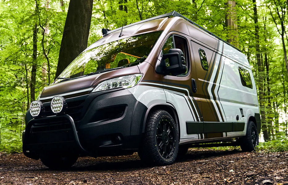 Fiat Ducato Camper mit schwarzen Linien und braun/weißer Folierung im Wald Vorderansicht links