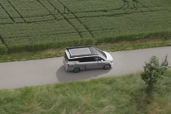 Mercedes EQV Elektro Camper mit modernem Linienmuster in Grau weiß – Drohnenansicht mit Feld